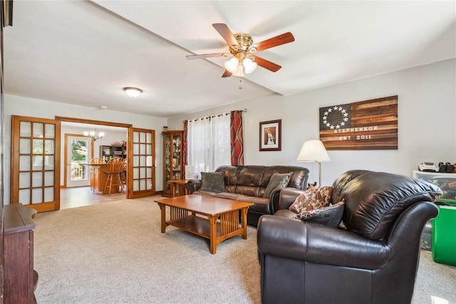 1207 E 4th St, Vinton, IA 52349 - living room with french doors, light colored carpet, ceiling fan, and a chandelier