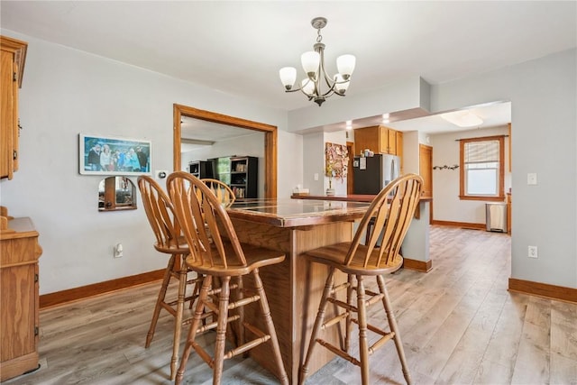 1207 E 4th St, Vinton, IA 52349 - bar with freestanding refrigerator, a chandelier, light wood-type flooring, and decorative light fixtures