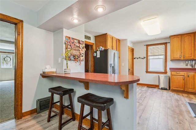 1207 E 4th St, Vinton, IA 52349 - kitchen with stainless steel refrigerator with ice dispenser, a breakfast bar area, and light wood-style floors