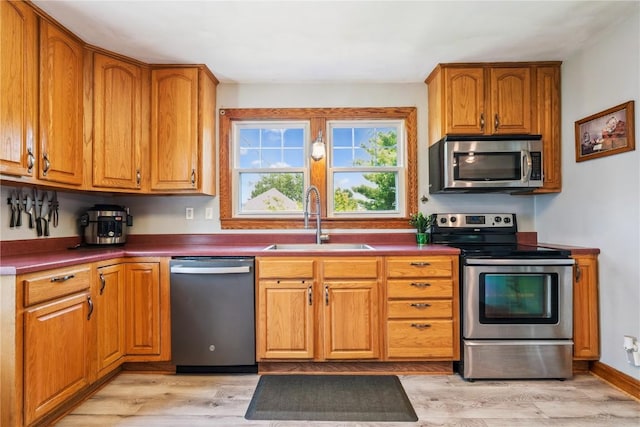 1207 E 4th St, Vinton, IA 52349 - kitchen featuring stainless steel appliances, light wood finished floors, brown cabinets, and dark countertops