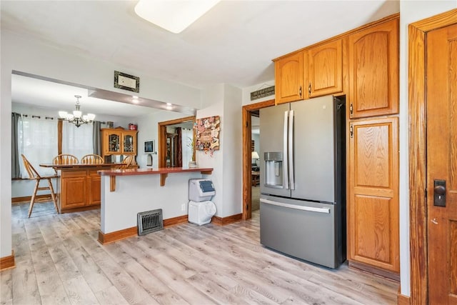 1207 E 4th St, Vinton, IA 52349 - kitchen featuring stainless steel refrigerator with ice dispenser, a peninsula, brown cabinetry, and a chandelier