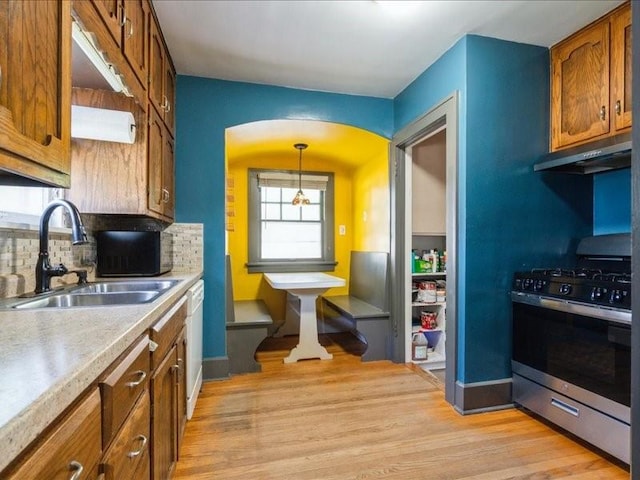 425 24th NE, Cedar Rapids, IA 52402 - kitchen featuring gas range, exhaust hood, backsplash, brown cabinets, and light wood finished floors