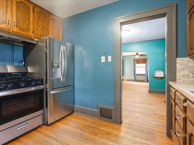425 24th NE, Cedar Rapids, IA 52402 - kitchen with appliances with stainless steel finishes, under cabinet range hood, light wood-type flooring, brown cabinetry, and ceiling fan