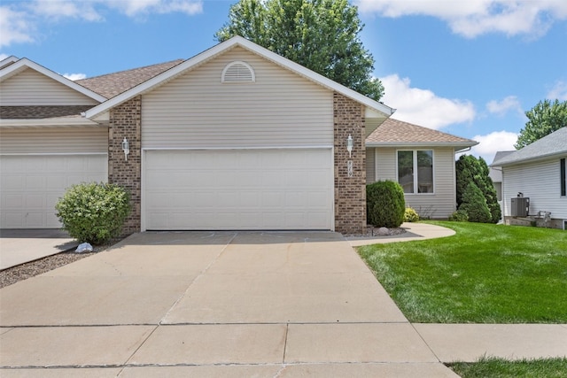 819 Winterberry Pl NE, Cedar Rapids, IA 52402 - view of front facade with brick siding, a garage, a front lawn, concrete driveway, and a shingled roof