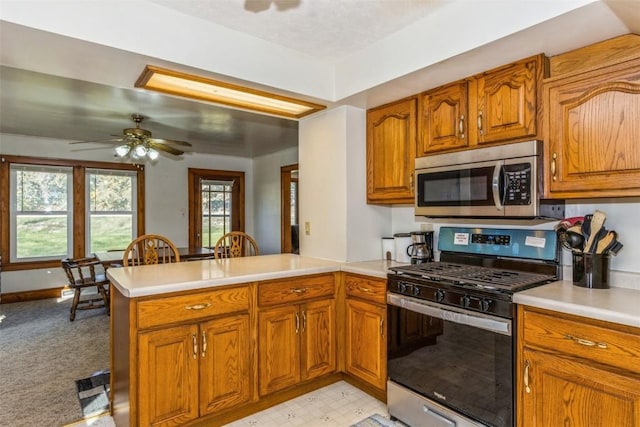 4100 Greens Grove Rd, Center Point, IA 52213 - kitchen with stainless steel appliances, a peninsula, light countertops, and brown cabinets