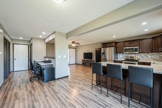 3212 Sherwood Pl, Marion, IA 52302 - kitchen with appliances with stainless steel finishes, a breakfast bar, dark brown cabinetry, light stone countertops, and light wood finished floors