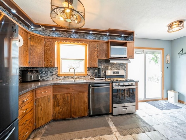 820 Hillview Dr, Marion, IA 52302 - kitchen with stainless steel appliances, decorative backsplash, brown cabinets, under cabinet range hood, and dark countertops