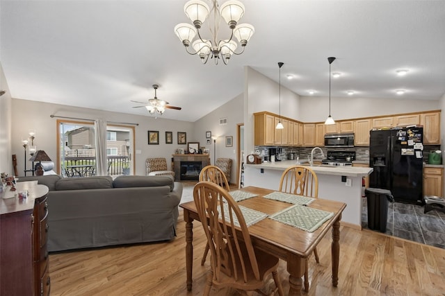 609 W Orange St, West Branch, IA 52358 - dining area featuring lofted ceiling, light wood finished floors, ceiling fan, a chandelier, and a fireplace