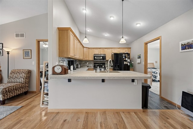 609 W Orange St, West Branch, IA 52358 - kitchen with black fridge with ice dispenser, lofted ceiling, a peninsula, light brown cabinets, and a breakfast bar area