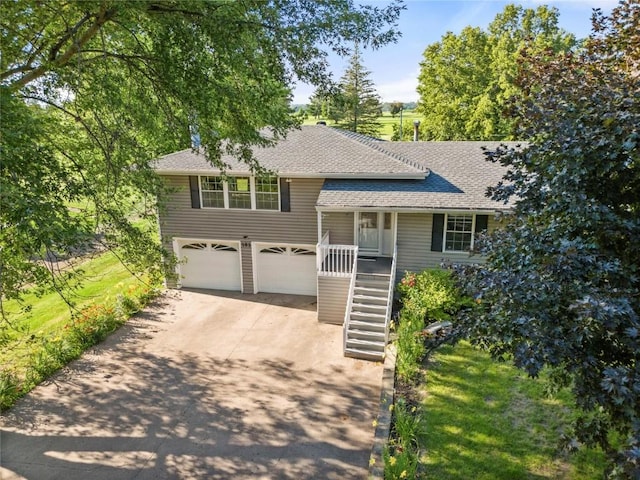 101 Golf Cir, Winfield, IA 52659 - tri-level home with stairs, driveway, a garage, a shingled roof, and a porch