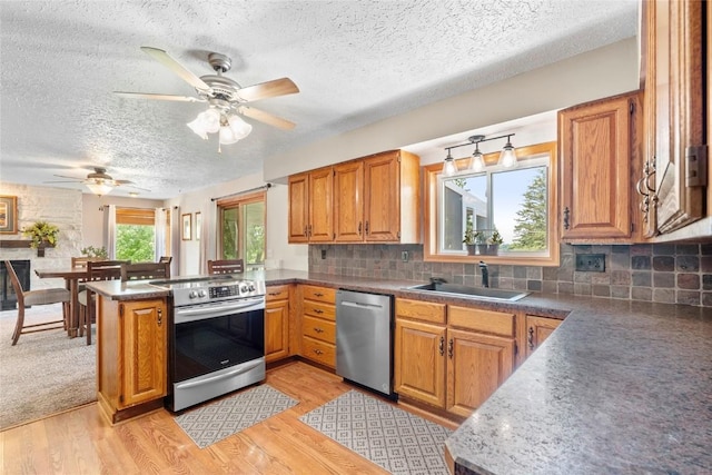 101 Golf Cir, Winfield, IA 52659 - kitchen featuring stainless steel appliances, a textured ceiling, a peninsula, a ceiling fan, and brown cabinetry