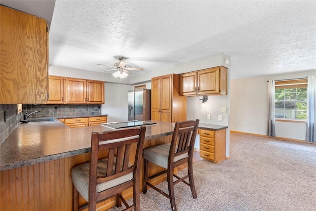 101 Golf Cir, Winfield, IA 52659 - kitchen featuring stainless steel refrigerator with ice dispenser, dark countertops, ceiling fan, a kitchen bar, and a textured ceiling