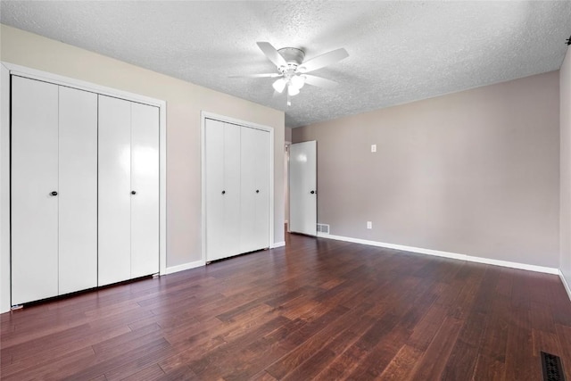 101 Golf Cir, Winfield, IA 52659 - unfurnished bedroom with wood finished floors, two closets, a textured ceiling, and a ceiling fan