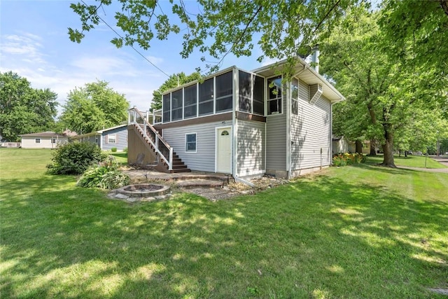 101 Golf Cir, Winfield, IA 52659 - rear view of property featuring an outdoor fire pit, stairway, a sunroom, and a lawn