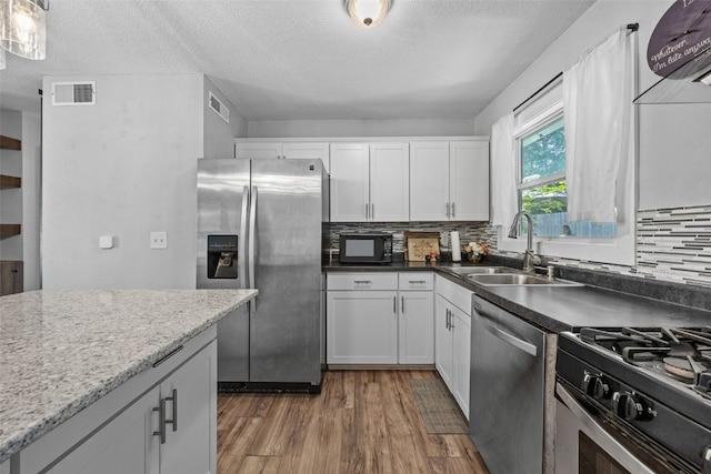665 Hillview Dr, Marion, IA 52302 - kitchen with appliances with stainless steel finishes, wood finished floors, a textured ceiling, backsplash, and white cabinets
