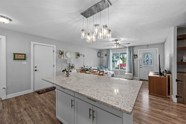 665 Hillview Dr, Marion, IA 52302 - kitchen with a textured ceiling, dark wood-style flooring, a ceiling fan, a kitchen island, and hanging light fixtures