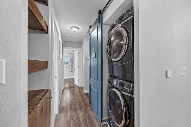 665 Hillview Dr, Marion, IA 52302 - laundry room featuring stacked washer / dryer, wood finished floors, and a textured wall