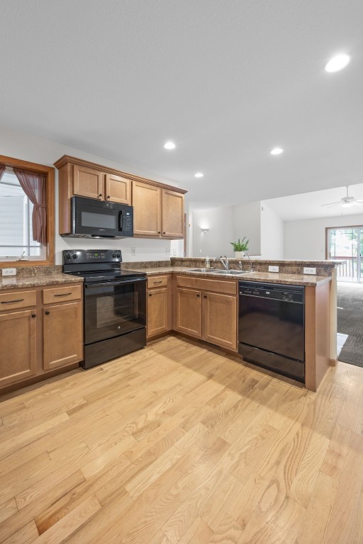 2054 Shortgrass Pl, Marion, IA 52302 - kitchen with black appliances, light wood-style floors, recessed lighting, brown cabinets, and a peninsula