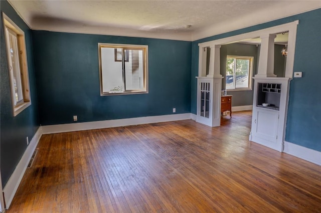 701 Hall Ave, Lowden, IA 52255 - unfurnished room featuring hardwood / wood-style flooring and decorative columns
