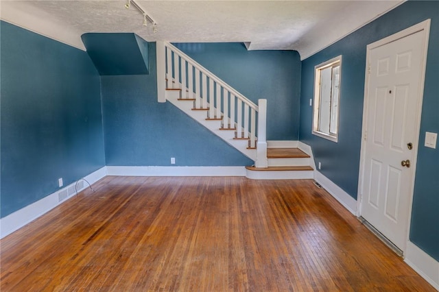 701 Hall Ave, Lowden, IA 52255 - entryway with stairs, hardwood / wood-style flooring, rail lighting, and a textured ceiling