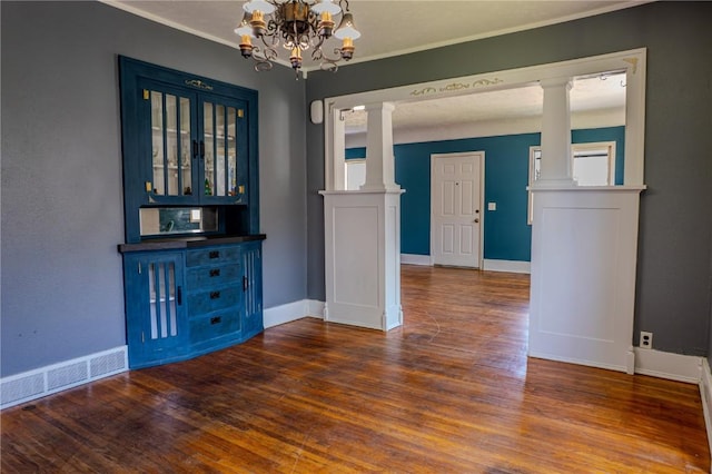 701 Hall Ave, Lowden, IA 52255 - spare room with decorative columns, a chandelier, wood finished floors, and crown molding