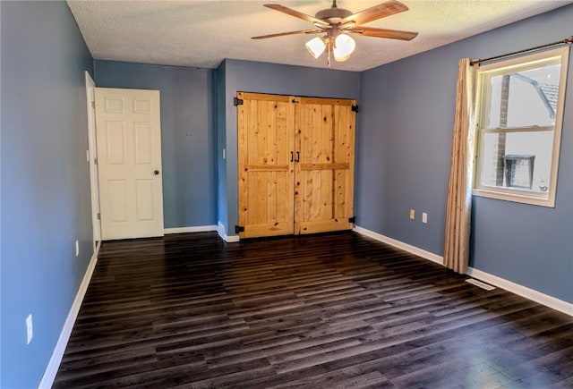 701 Hall Ave, Lowden, IA 52255 - unfurnished bedroom featuring dark wood-type flooring, a textured ceiling, a ceiling fan, and a closet