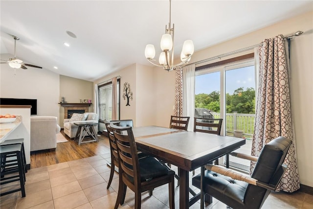 8313 Monterey Dr NE, Cedar Rapids, IA 52402 - dining room with a chandelier, ceiling fan, a fireplace, vaulted ceiling, and light tile patterned flooring