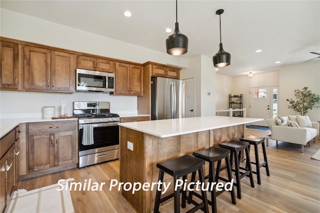 4620 Preston Ln, Iowa City, IA 52246 - kitchen featuring appliances with stainless steel finishes, light wood-style floors, a center island, brown cabinetry, and light countertops