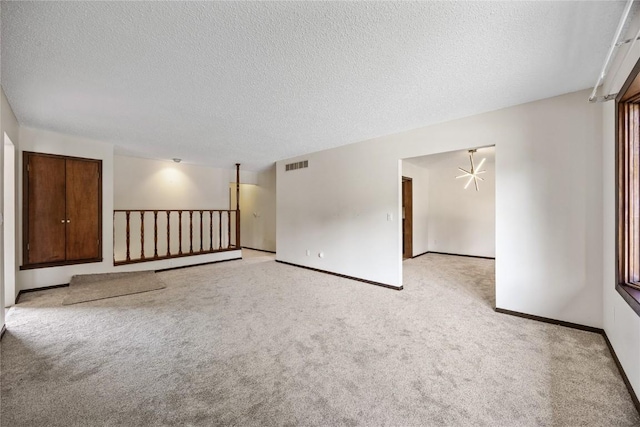 1131 Penkridge Dr, Iowa City, IA 52246 - unfurnished room with light carpet, a textured ceiling, and a chandelier