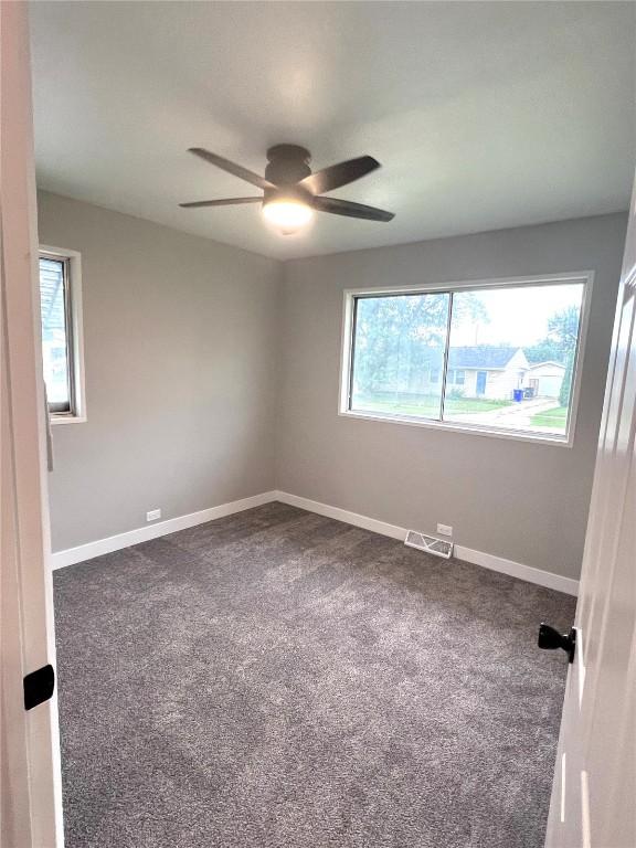 1705 NE Texas Ave, Cedar Rapids, IA 52402 - empty room featuring ceiling fan and dark colored carpet