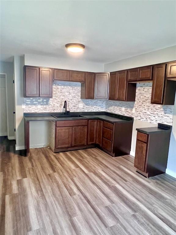 1705 NE Texas Ave, Cedar Rapids, IA 52402 - kitchen featuring tasteful backsplash, light wood-style floors, dark countertops, and dark brown cabinetry