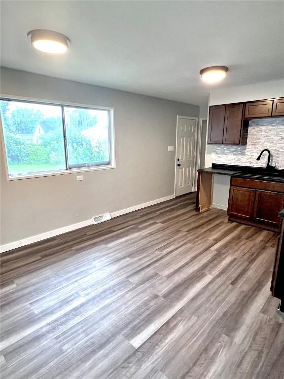 1705 NE Texas Ave, Cedar Rapids, IA 52402 - kitchen featuring backsplash, wood finished floors, dark countertops, and dark brown cabinetry