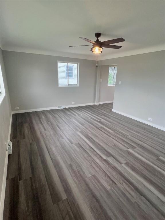 1705 NE Texas Ave, Cedar Rapids, IA 52402 - empty room with healthy amount of natural light, dark wood-type flooring, and a ceiling fan