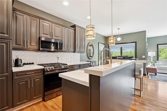 5512 Black Oak Dr NE, Cedar Rapids, IA 52411 - kitchen featuring stainless steel appliances, light countertops, light wood-style floors, backsplash, and a kitchen island with sink