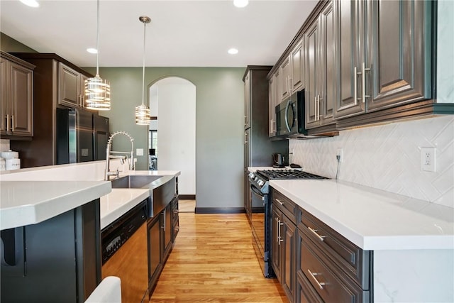 5512 Black Oak Dr NE, Cedar Rapids, IA 52411 - kitchen featuring appliances with stainless steel finishes, arched walkways, decorative backsplash, light countertops, and light wood finished floors
