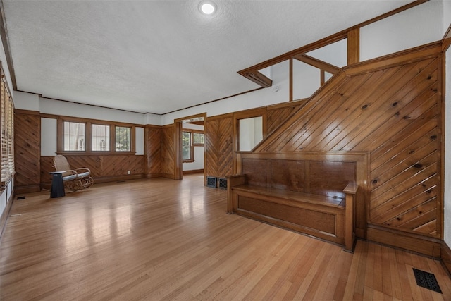 308 Main St, Norway, IA 52318 - unfurnished living room featuring light wood-style flooring, wood walls, and a textured ceiling