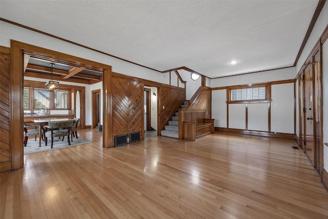 308 Main St, Norway, IA 52318 - unfurnished living room featuring ornamental molding, stairway, light wood finished floors, healthy amount of natural light, and a textured ceiling