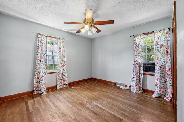 107 Spruce St, Blairstown, IA 52209 - unfurnished room with wood finished floors, a textured ceiling, a ceiling fan, and cooling unit