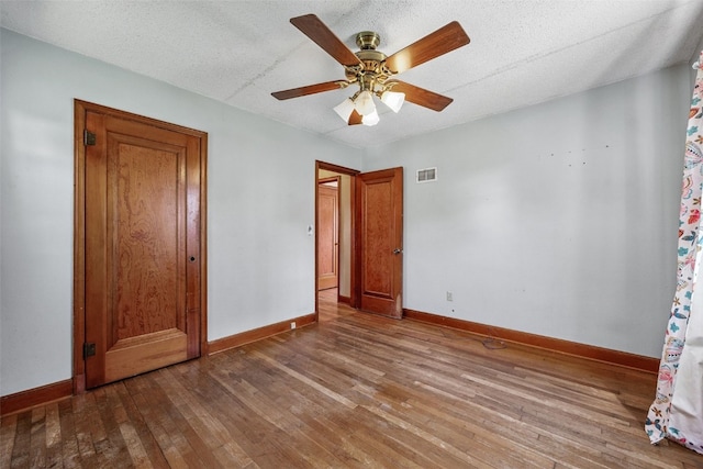 107 Spruce St, Blairstown, IA 52209 - unfurnished bedroom featuring hardwood / wood-style floors, ceiling fan, and a textured ceiling