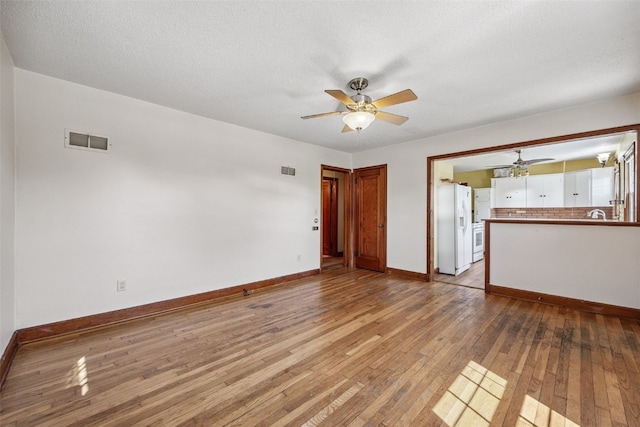 107 Spruce St, Blairstown, IA 52209 - unfurnished living room featuring ceiling fan, hardwood / wood-style floors, and a textured ceiling