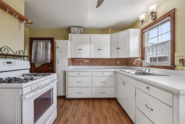 107 Spruce St, Blairstown, IA 52209 - kitchen featuring white gas range, a textured ceiling, light countertops, backsplash, and light wood-type flooring
