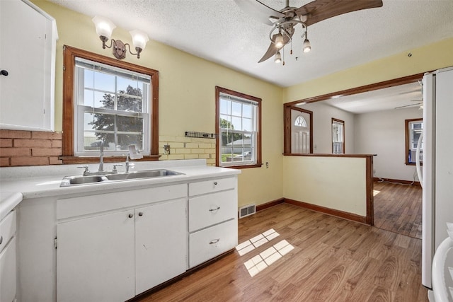 107 Spruce St, Blairstown, IA 52209 - kitchen featuring ceiling fan, light wood finished floors, white cabinets, light countertops, and a textured ceiling