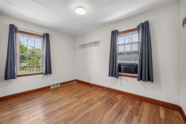 107 Spruce St, Blairstown, IA 52209 - unfurnished room with wood-type flooring, healthy amount of natural light, a textured ceiling, and cooling unit