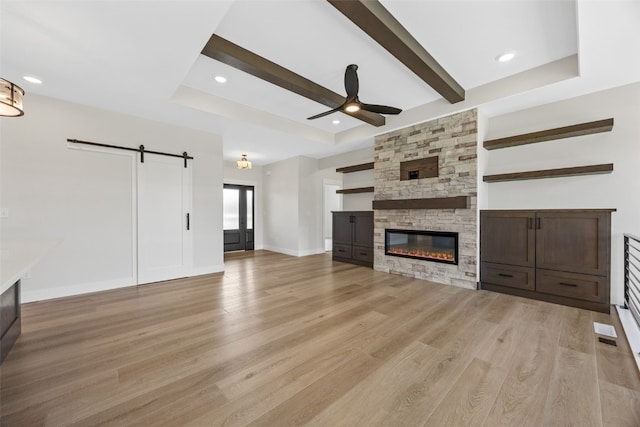 4018 Peridot Dr, Marion, IA 52302 - unfurnished living room featuring a barn door, a ceiling fan, light wood-style floors, a stone fireplace, and recessed lighting