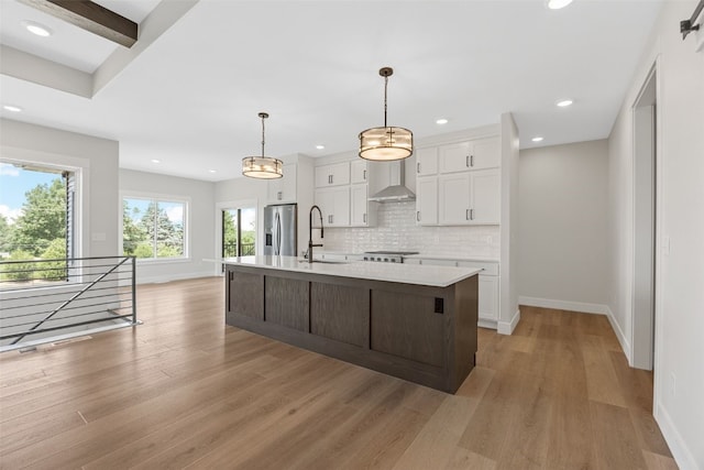4018 Peridot Dr, Marion, IA 52302 - kitchen with stainless steel fridge with ice dispenser, white cabinets, light countertops, tasteful backsplash, and wall chimney exhaust hood