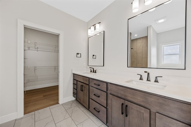 4018 Peridot Dr, Marion, IA 52302 - bathroom featuring double vanity, marble look tiles, a spacious closet, and tiled shower