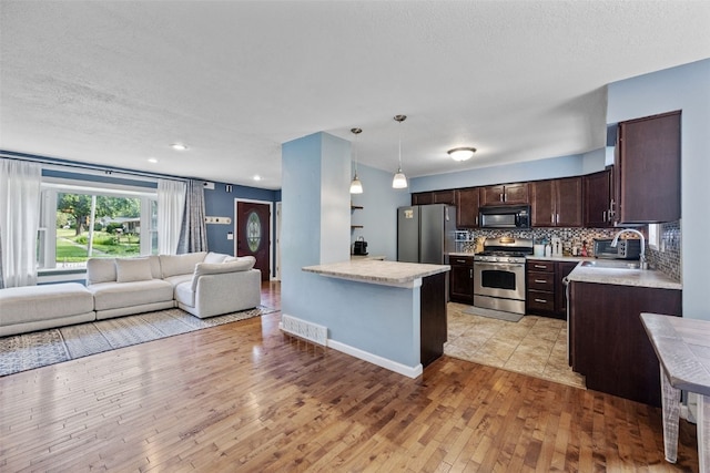 1608 10th St, Coralville, IA 52241 - kitchen with appliances with stainless steel finishes, dark brown cabinets, open floor plan, light countertops, and a textured ceiling