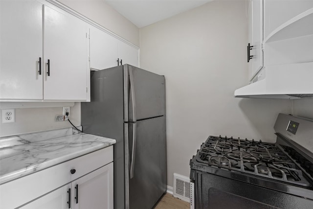 2225 SE Mount Vernon Rd, Cedar Rapids, IA 52403 - kitchen featuring gas stove, freestanding refrigerator, under cabinet range hood, white cabinets, and light wood-style floors