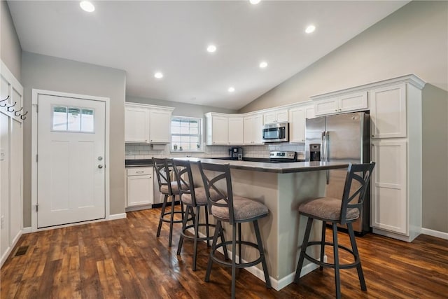 3016 Sherwood Dr, Marion, IA 52302 - kitchen with stainless steel appliances, dark countertops, dark wood-type flooring, tasteful backsplash, and vaulted ceiling