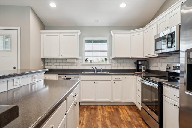 3016 Sherwood Dr, Marion, IA 52302 - kitchen with appliances with stainless steel finishes, wood finished floors, white cabinetry, recessed lighting, and lofted ceiling